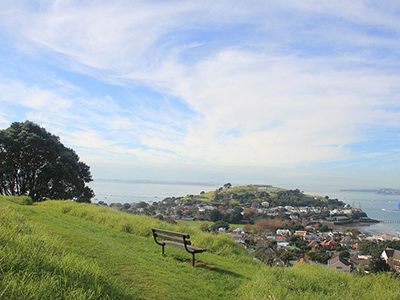 Park bench on the side of a NZ mountain of a sunny day, blue, clouds